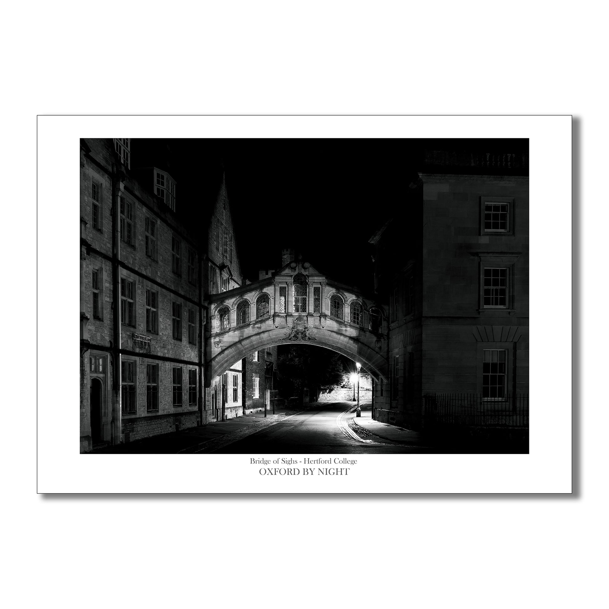 A dramatic night time photographic art print of the Bridge of Sighs, Oxford. The black and white image showcases the intricate architecture of the bridge and highlights the play of light and shadow