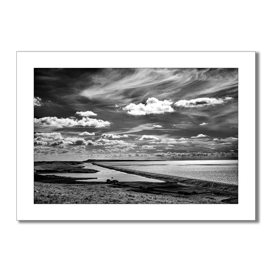 Dramatic black and white landscape art photograph of Chesil Beach, Dorset, showcasing the vast expanse of shingle and the interplay of light and shadow